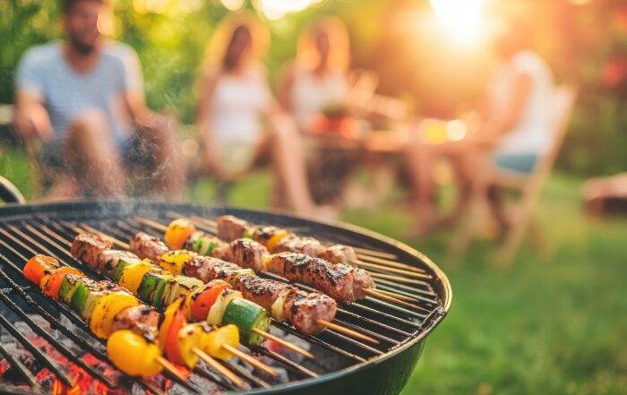 Friends gather in a vibrant backyard during sunset, enjoying a barbecue. Colorful skewers with meat and vegetables sizzle on the grill, creating a delightful atmosphere.